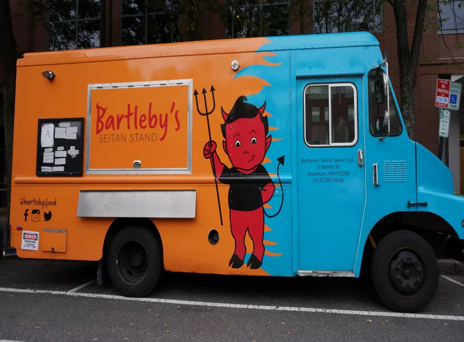 The big blue and orange Bartleby's food truck on the street.