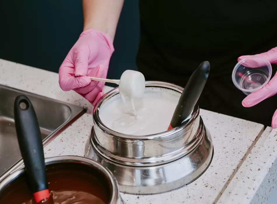 Banana pop dessert being dipped in white chocolate