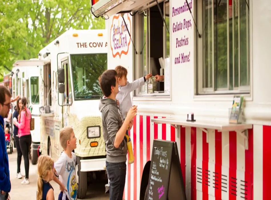 Side view of the Gotta Lotta Gelato truck with a father and daughter ordering gelato in front of the service window