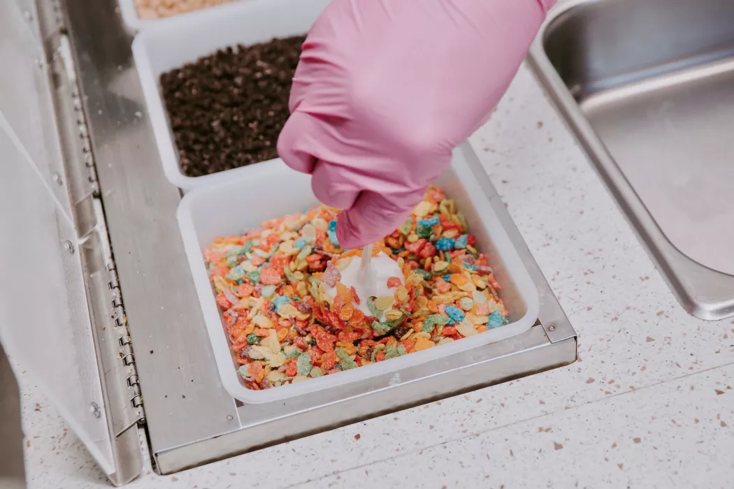 Banana pop being made with white chocolate topped with Fruity Pebbles